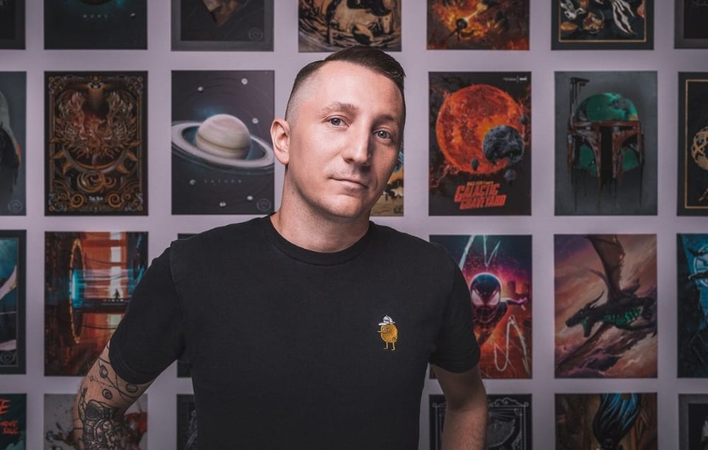 Piotr Kacala in front of a wall of Displate metal posters